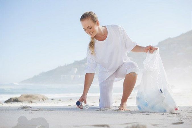 Frau sammelt Müll am Strand