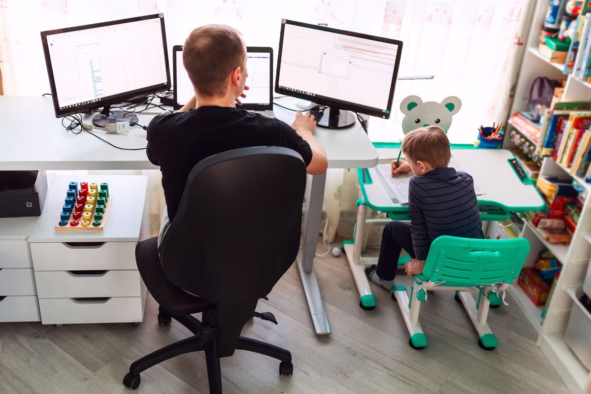 Arbeitender Vater mit Kind am Tisch Arbeitender Vater mit Kind am Tisch